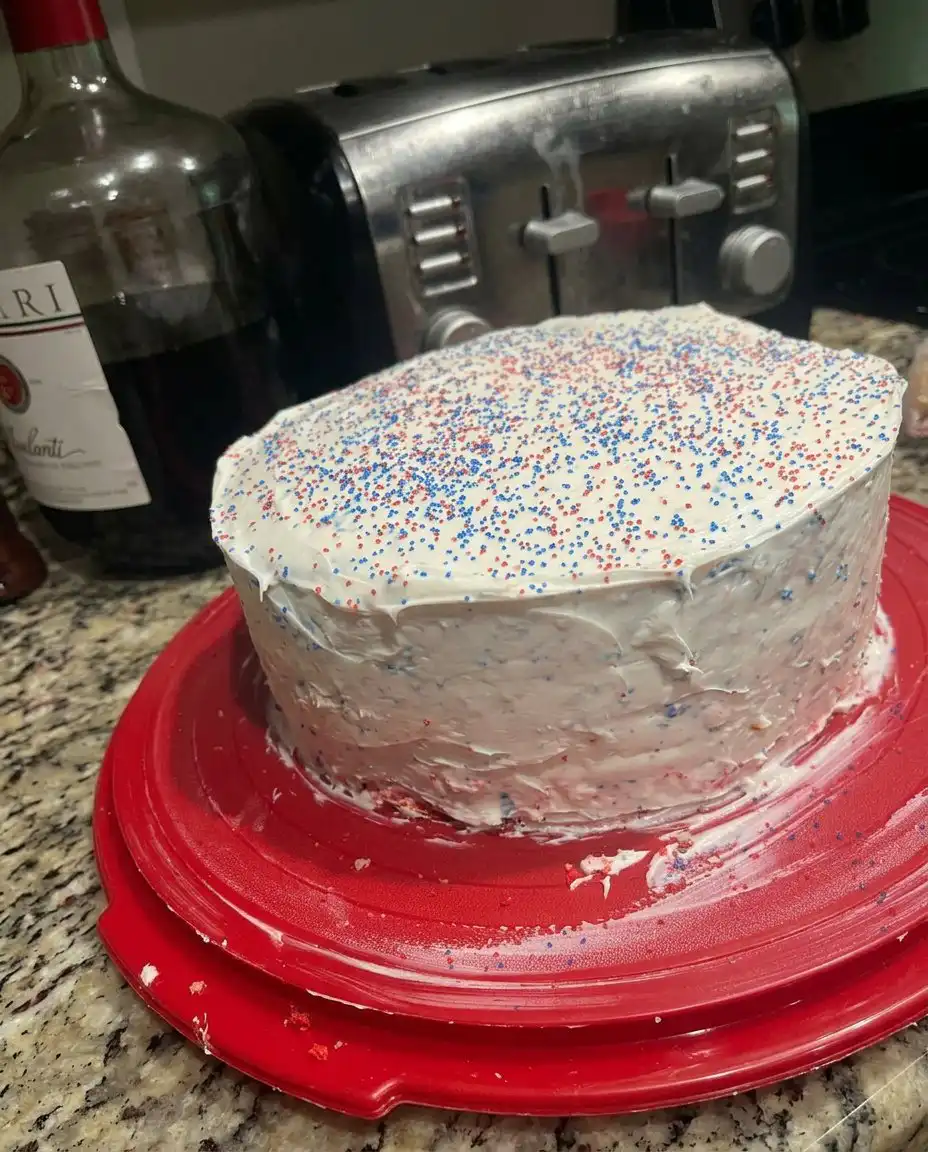 A pastry chef using a serrated knife to level red cake layers