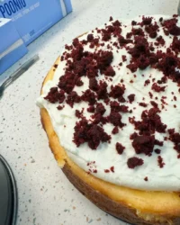 A slice of red velvet cheesecake showing the distinct red cake base and white cheesecake layer