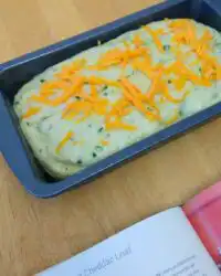 A golden brown loaf of Green Onion Zucchini Cheddar Quick Bread on a wire rack