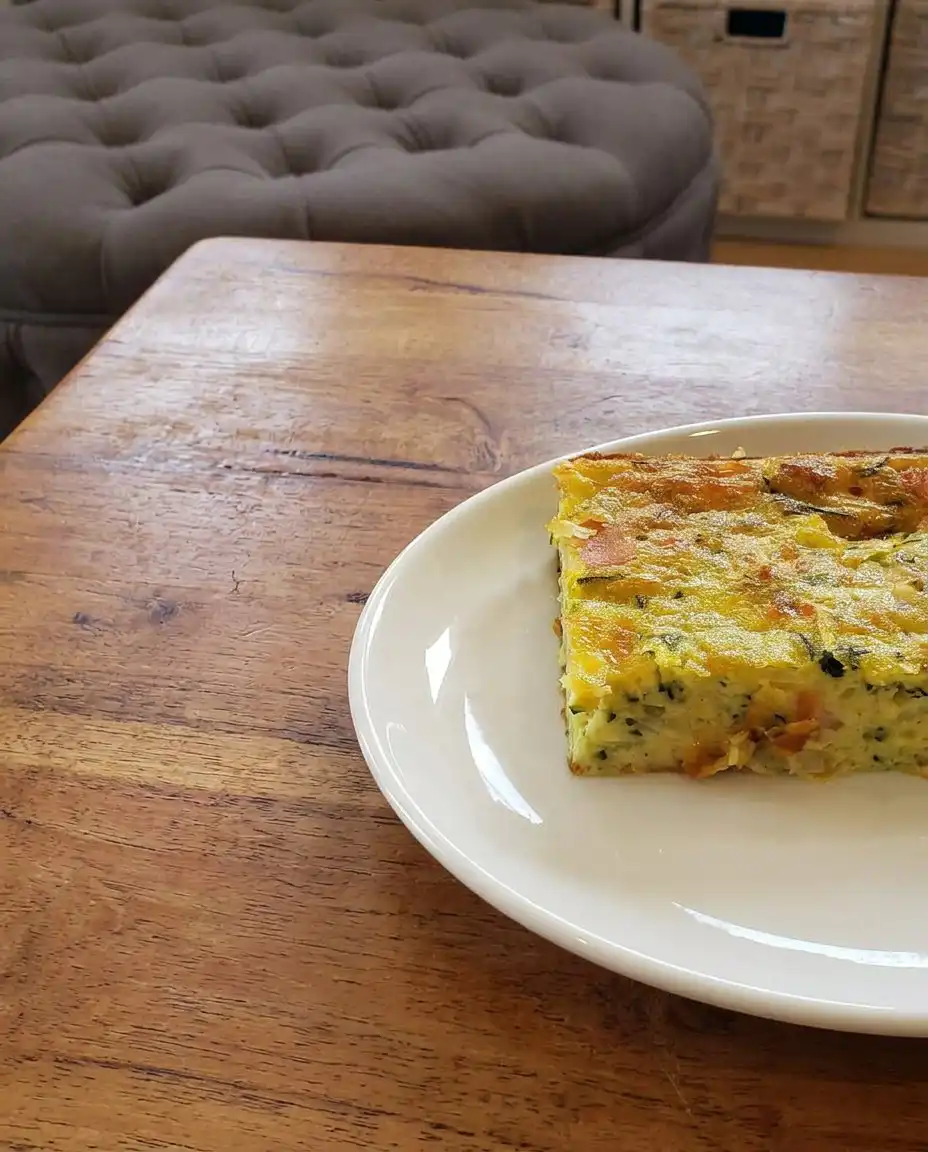 A slice of zucchini pie on a plate with a side salad