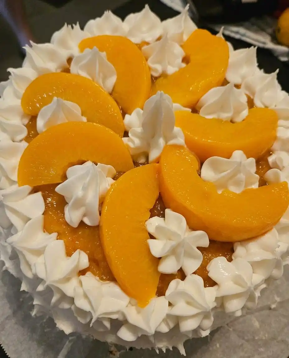 A clean slice of Peaches and Cream Layer Cake served on a white porcelain plate.