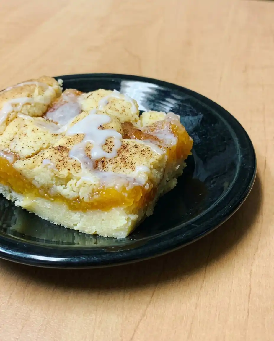 Peach Coffee Cake 16 A square slice of Peach Coffee Cake served on a white plate with coffee.