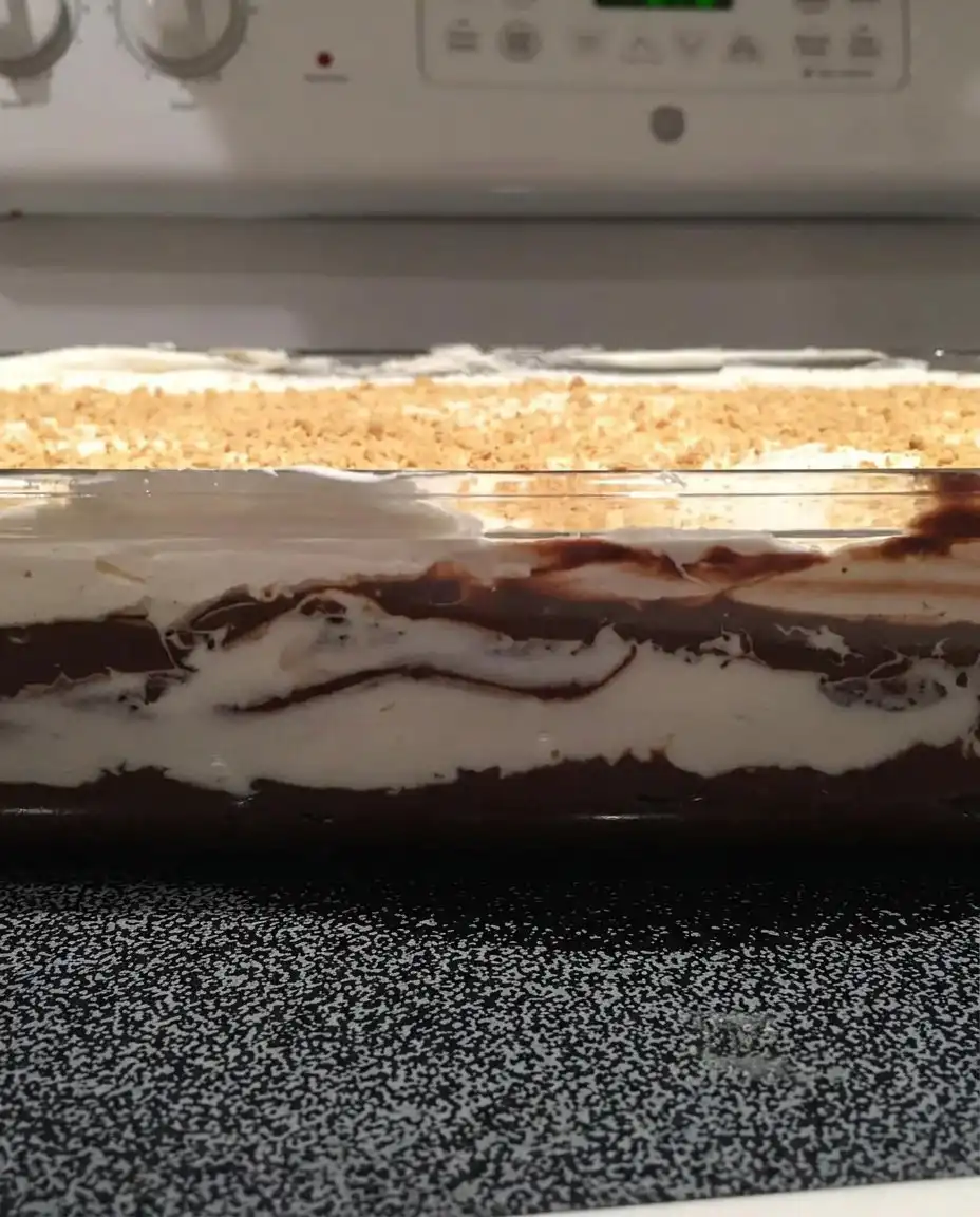 Chocolate Delight 14 A single square slice of Chocolate Delight on a white plate with a clean vertical cut showing all layers.