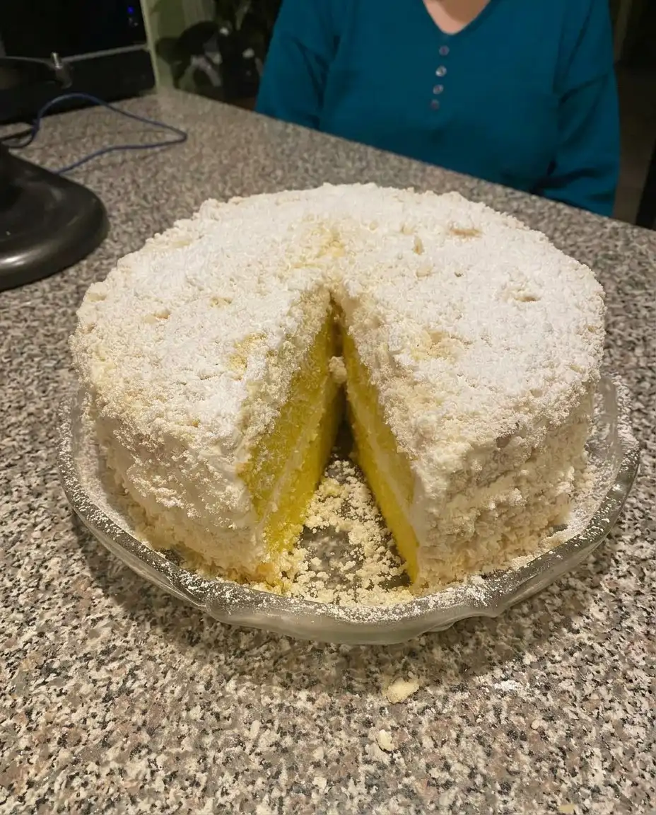 A slice of Italian Lemon Cream Cake served on a white plate with a fork