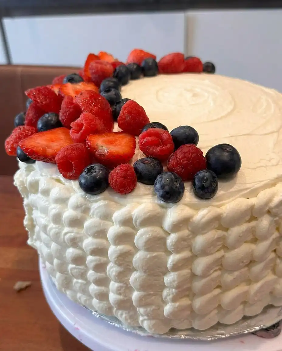 Serving a beautiful three layer patriotic berry cake on a white platter