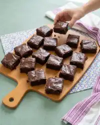 A close up shot of a sliced chocolate zucchini cake with chocolate chips on a white plate.