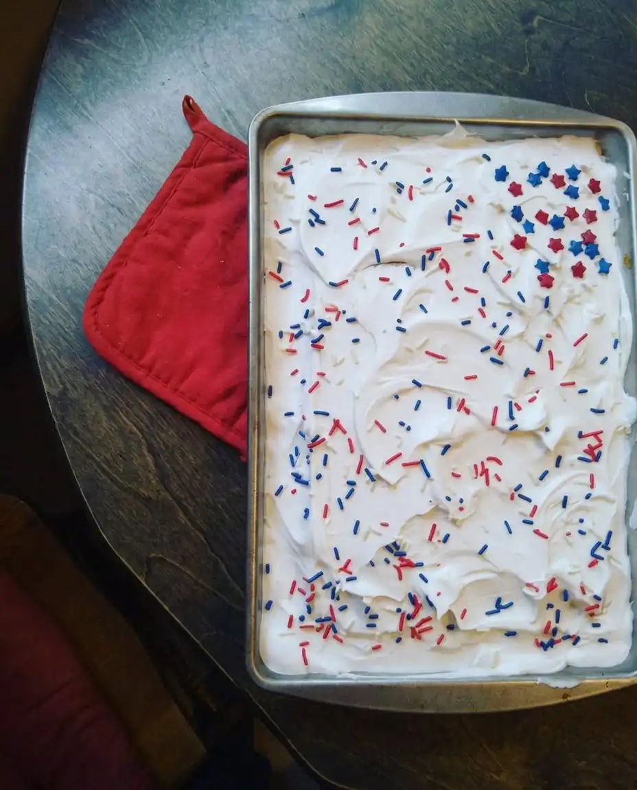 Red, White & Blue Patriotic Poke Cake 14 A square slice of red white and blue poke cake on a white plate