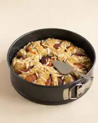 A freshly baked Sour Cream Peach Coffee Cake in a springform pan showing a golden brown crust.
