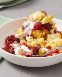 A large scoop of strawberry cheesecake dump cake with gooey center