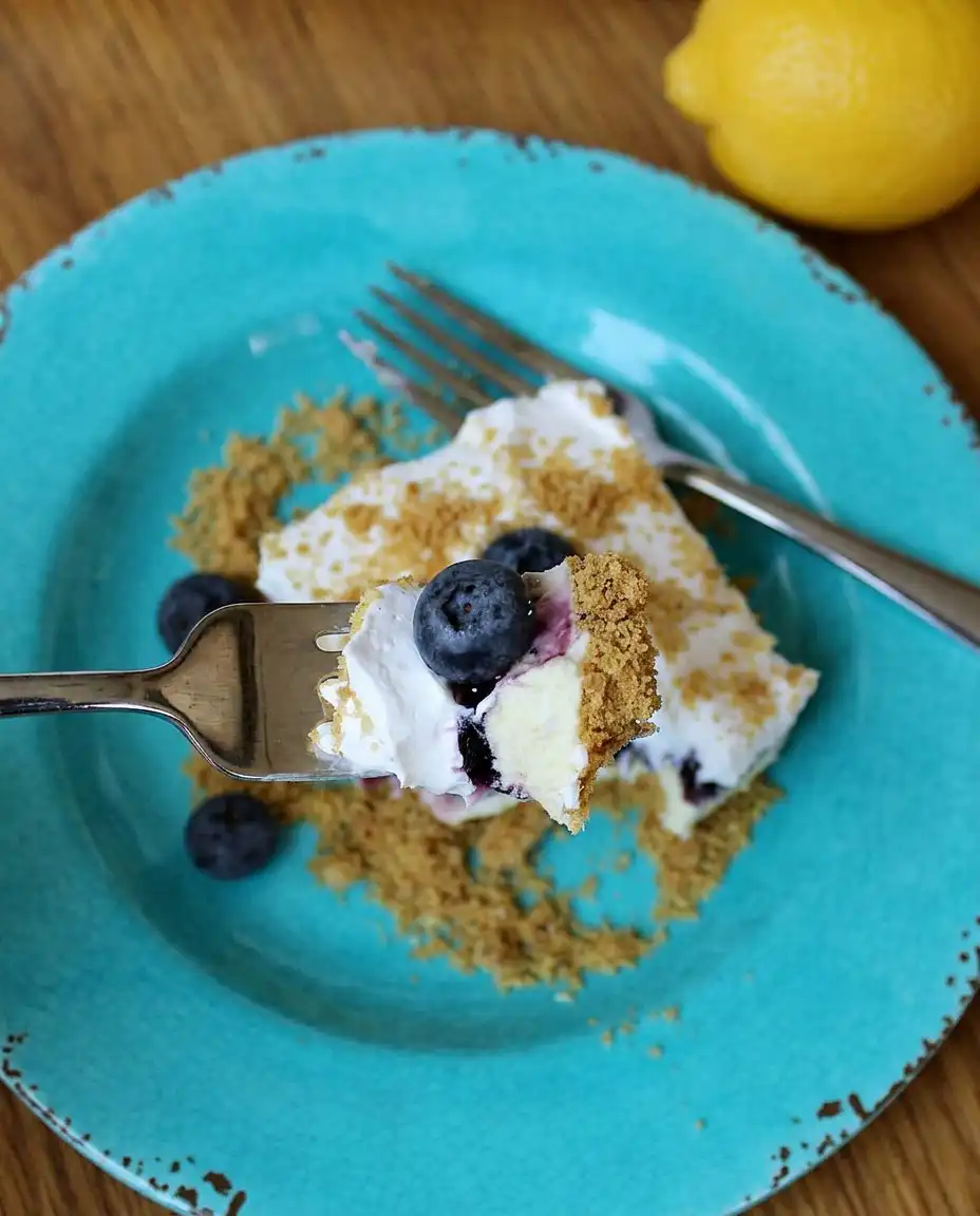 No Bake Lemon Blueberry Dessert 13 The process of spreading the lemon pudding layer onto the graham cracker crust with an offset spatula.