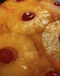 A close up shot of a sliced pineapple layer cake showing the moist crumb and yellow custard filling.