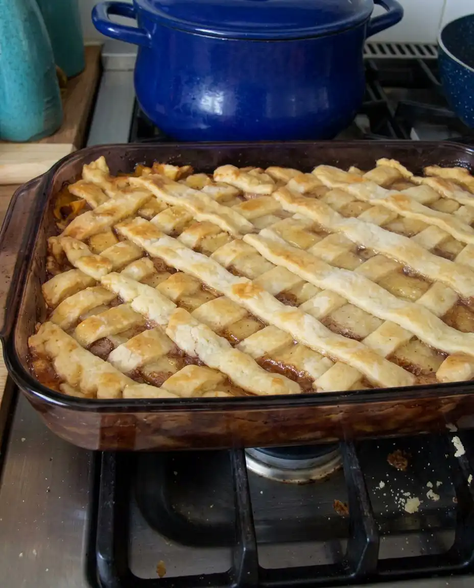 A serving of warm peach cobbler in a bowl with a scoop of vanilla ice cream