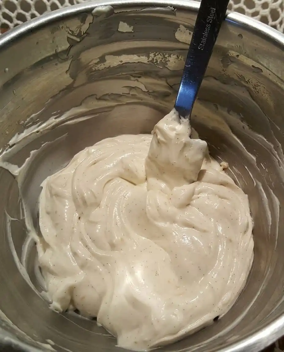 Close up of cream cheese and powdered sugar being beaten into a smooth satin consistency