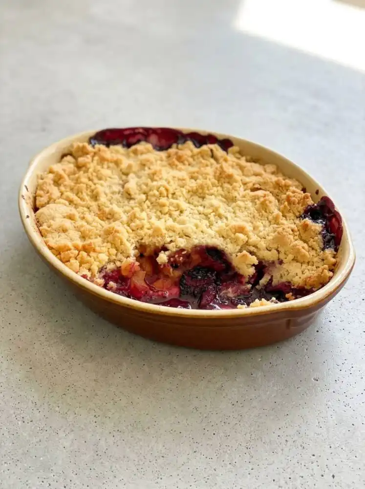A golden brown Blackberry Apple Dump Cake bubbling in a white ceramic dish