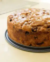 A slice of freshly baked Harvest Apple Cake showing dense apples and chopped pecans