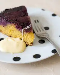 A warm slice of Blackberry Upside Down Cake showing its caramelized fruit layer and golden sponge crumb.