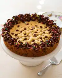 A close up photo of a Brown Butter Chocolate Chip Cookie Cake slice being cut from the pan