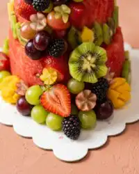 A chef carving round cylinders of red and yellow melon for a Watermelon Fruit Cake Tower.