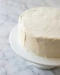 A golden-brown classic carrot cake with cream cheese frosting sits ready on a wire rack.