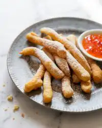 Classic Funnel Cake Fries dusted with sweet powdered sugar on a plate