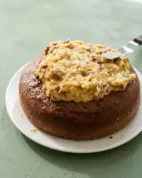 A thick slice of Classic German Chocolate Cake with Coconut Pecan Frosting served on a white vintage plate.