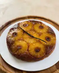 Freshly baked Pineapple Upside-Down Cake showing glossy caramelized fruit topping on a white platter.
