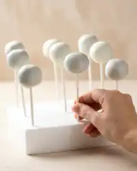 A close up shot of flawless Oreo Cake Pops coated in white candy melts on a white tray.