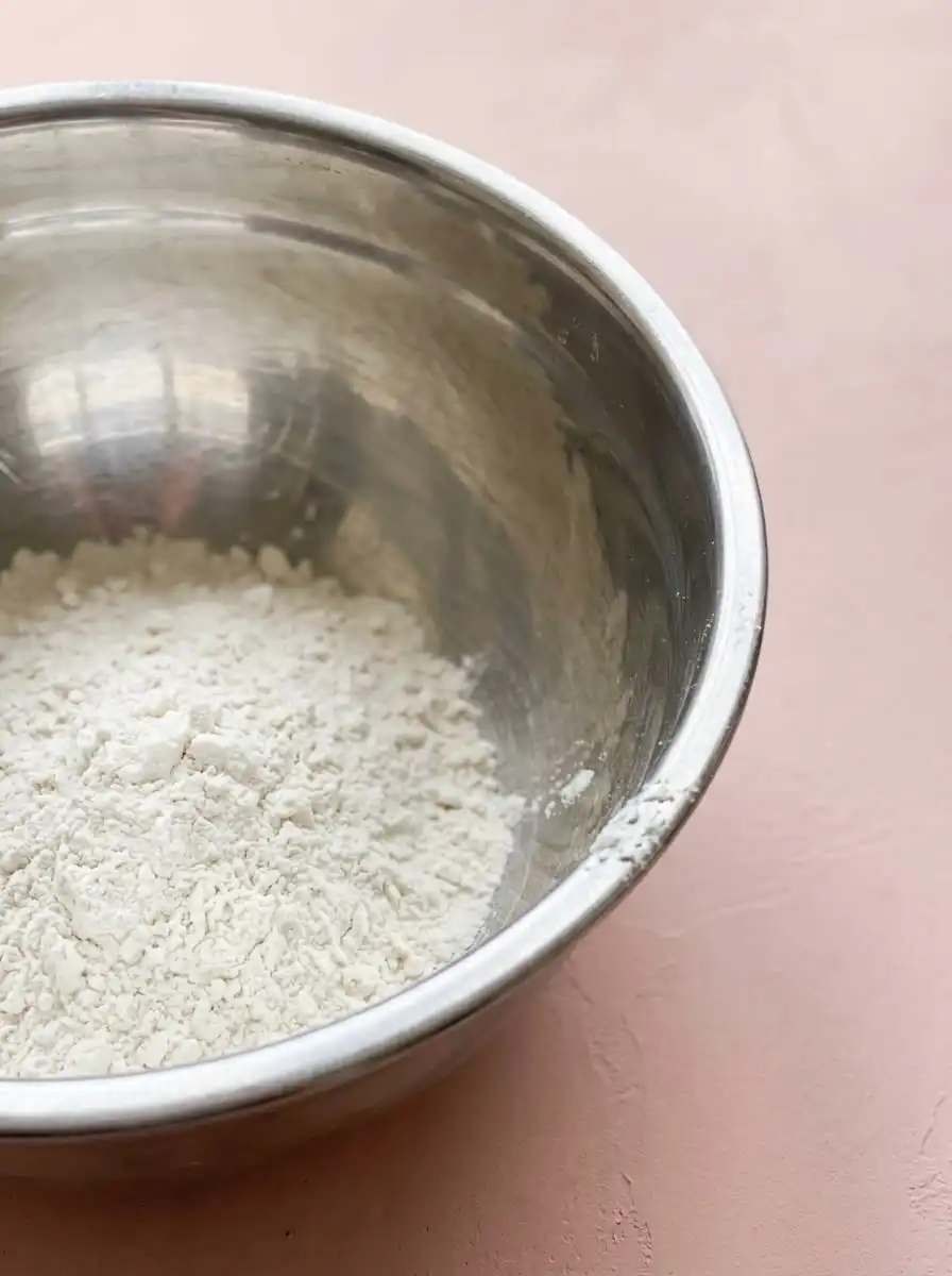 Fresh strawberries, evaporated milk, flour, and an egg arranged on a wooden kitchen counter