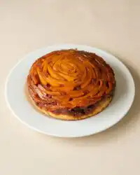 A golden brown Mango Upside Down Cake freshly inverted on a white serving plate.