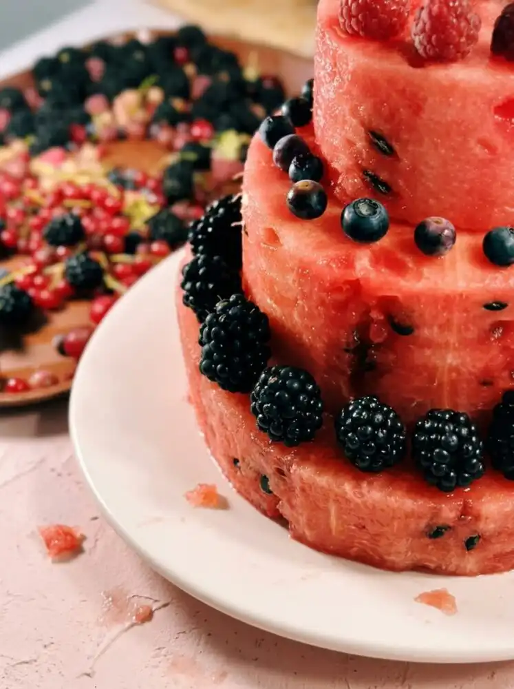 Home - Melt Cake - Baking that Melts in Your Mouth 8 A beautiful Watermelon and Berry Layer Cake stacked on a white platter surrounded by fresh fruit.
