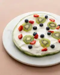 A colorful Watermelon Pizza Cake topped with fresh berries and creamy yogurt