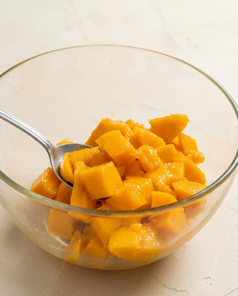 A rustic wooden table with fresh mango slices softened butter eggs and flour for Mango Butter Cake