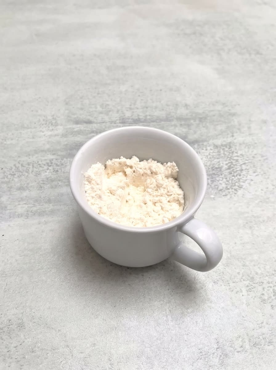 1-Minute Vanilla Mug Cake 14 Pantry ingredients for making a quick 1-Minute Vanilla Mug Cake on a wooden counter
