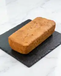 A golden moist Mango Butter Cake loaf resting on a black wire cooling rack