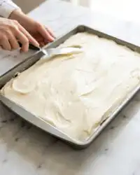 A slice of delicious Pumpkin Spice Cake topped with creamy cream cheese frosting and chopped pecans.