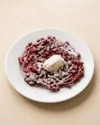 A beautiful golden fried Red Velvet Funnel Cake dusted with powdered sugar on a serving plate.