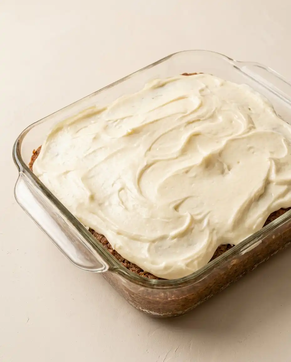 A square slice of Pineapple Sheet Cake with Cream Cheese Frosting on a plate next to Turkish coffee.