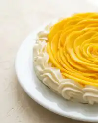 A beautiful sliced Mango Flower Crown Cake displayed on a marble cake stand.