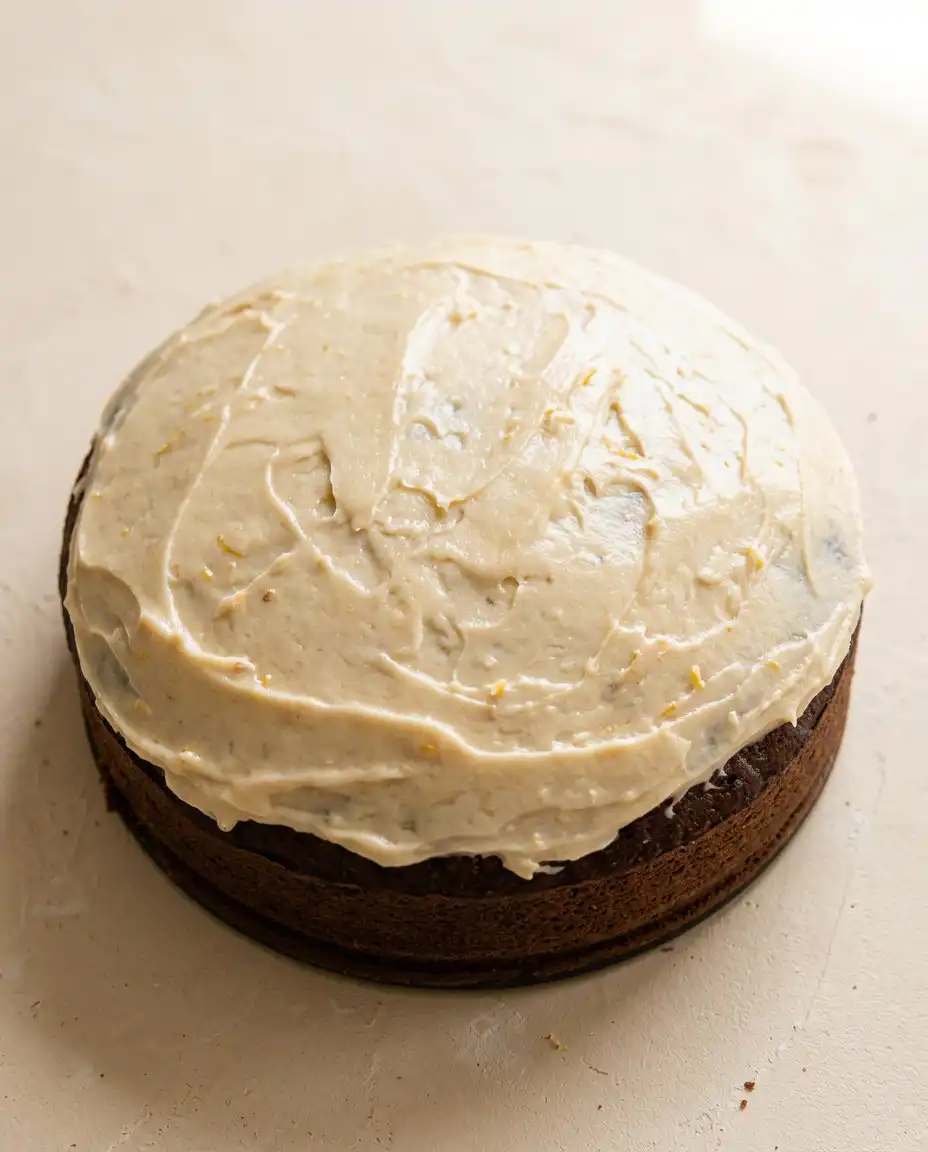 Slicing a Marzipan Carrot Topped Cake with a warm knife to reveal the tender crumb and frosting layers.