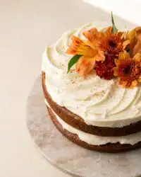 Slices of decadent Brown Butter Pumpkin Cake with cream cheese frosting and caramel filling on a rustic stand.
