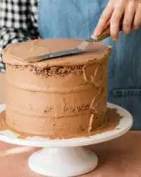 A three layer triple chocolate zucchini cake resting on a wire cooling rack