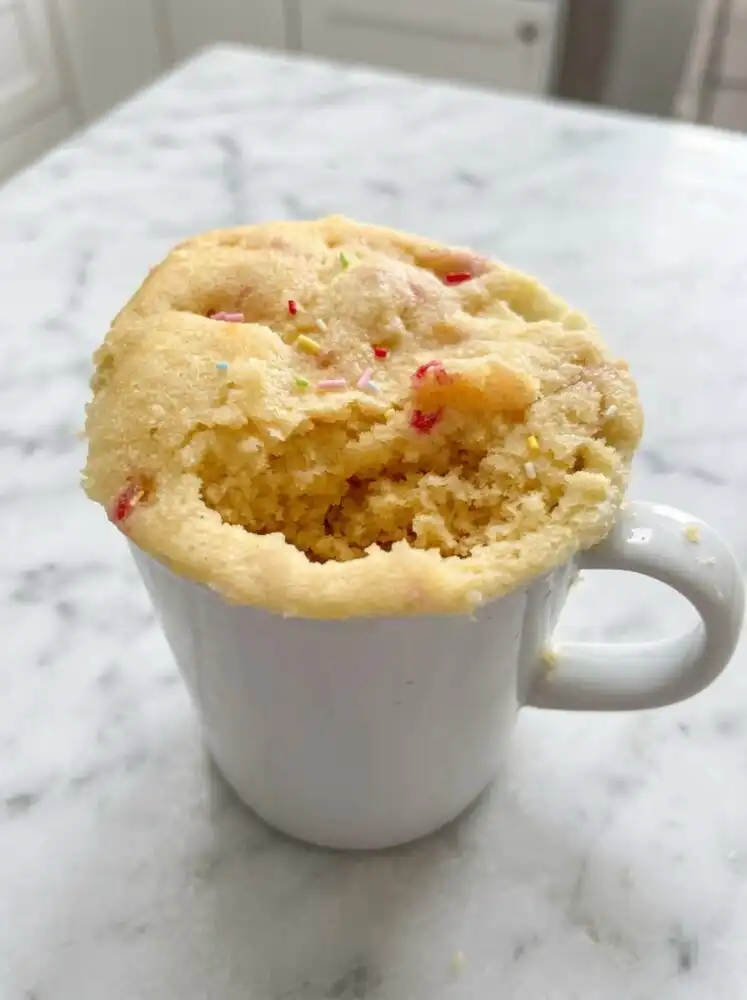 Home - Melt Cake - Baking that Melts in Your Mouth 5 A warm 1-Minute Vanilla Mug Cake topped with colorful sprinkles inside a blue ceramic mug
